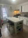 Kitchen featuring stove, radiator, open shelves, and white cabinets