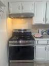 Kitchen with gas stove, extractor fan, white cabinets, and backsplash