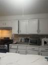 Kitchen featuring range, exhaust hood, white cabinetry, and decorative backsplash