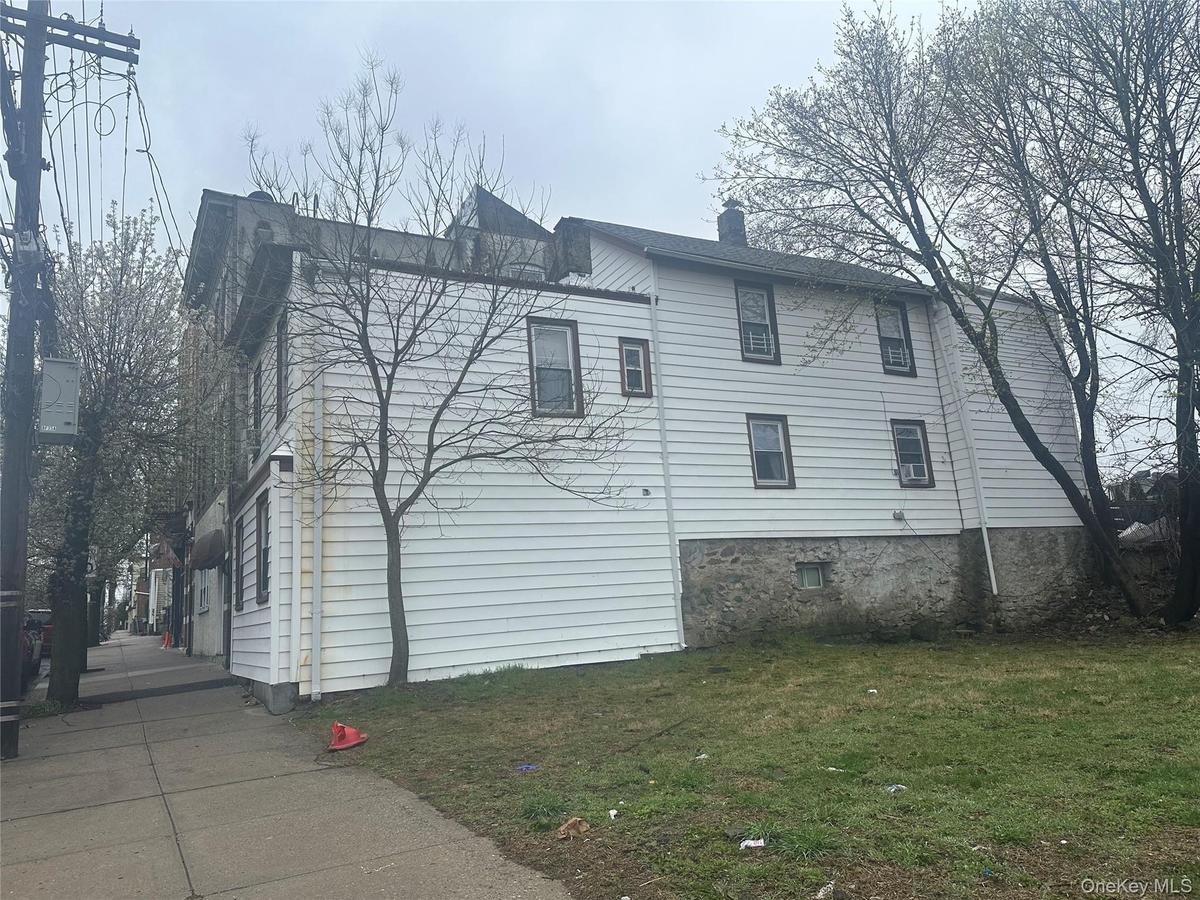 View of side of home with a chimney and a yard