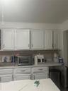 Kitchen with a sink, light countertops, decorative backsplash, and white cabinetry
