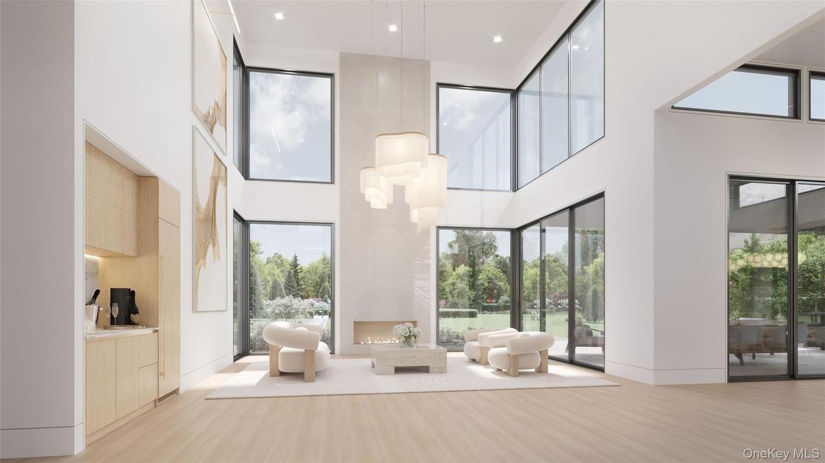 The great room blends refined interiors with the surrounding landscape; anchored by a sleek linear fireplace and complemented by a built-in bar with w