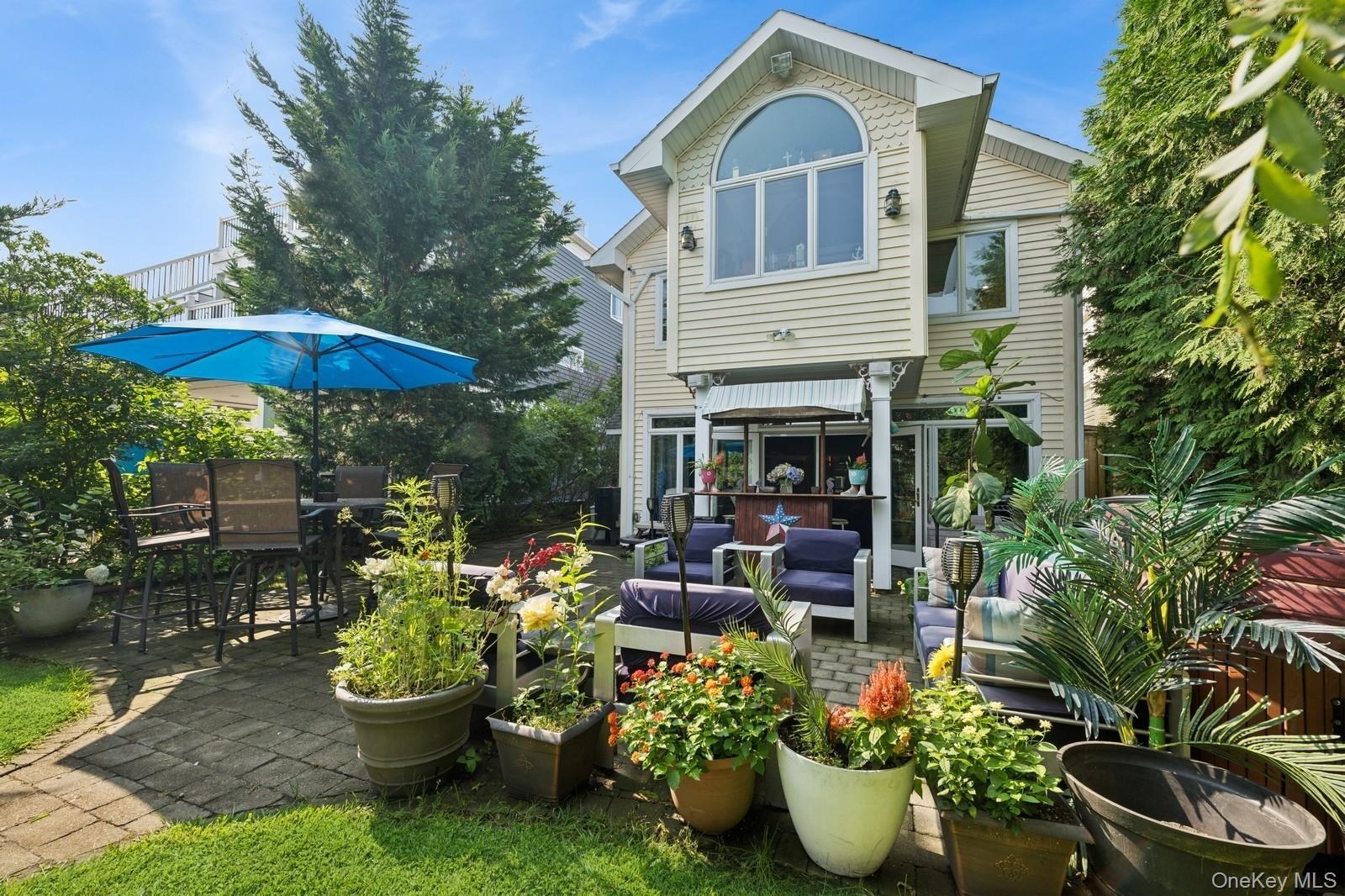 Exterior featuring a spacious patio with paver flooring, a built-in outdoor bar, and an upper-level window with an arched transom