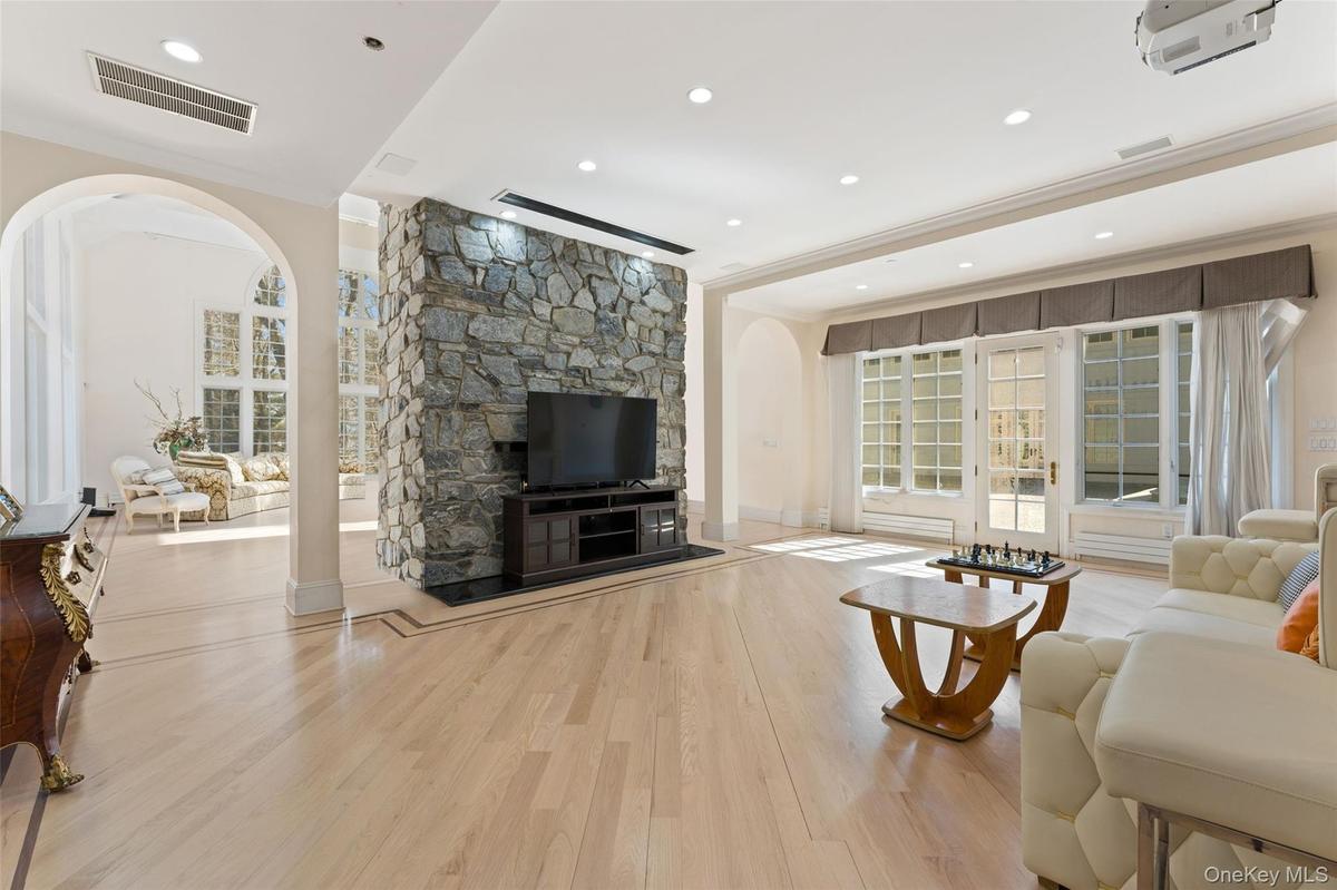 Living area featuring arched walkways, light wood-style flooring, crown molding, and recessed lighting