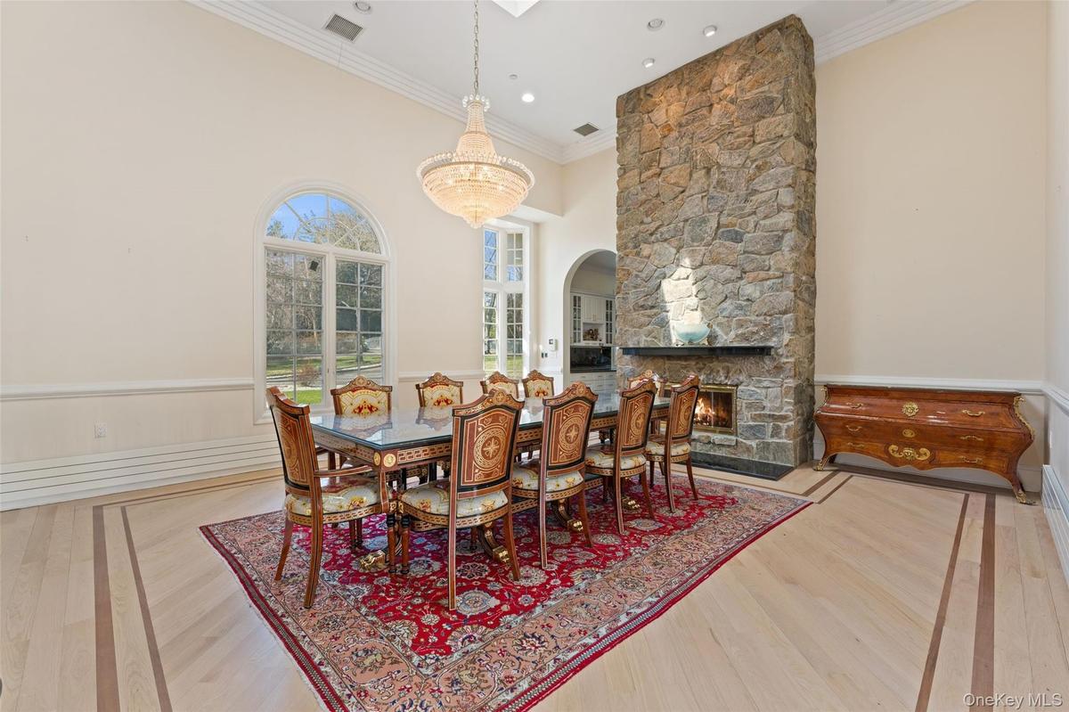 Dining area featuring hardwood floors with an inlaid border, a stone fireplace, and arched windows