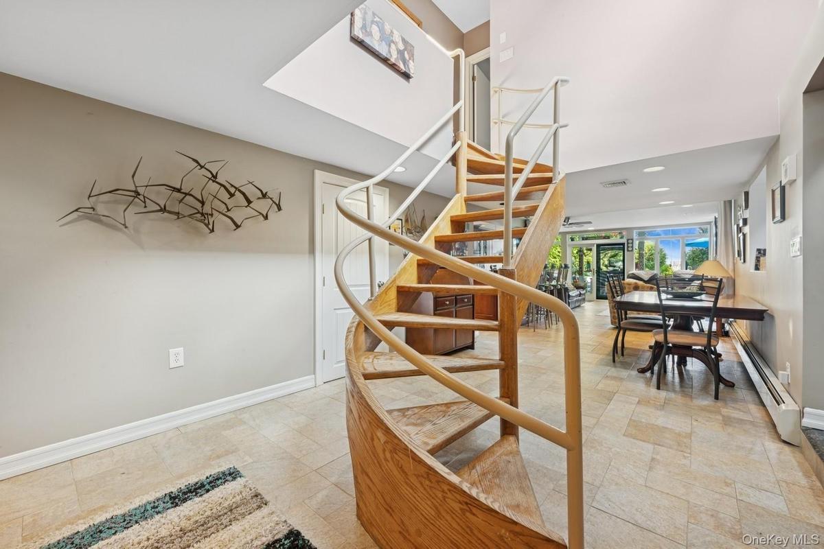 Spiral staircase with wood treads and a light-toned railing, complemented by large format floor tiles
