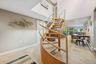 Spiral staircase with wood treads and a light-toned railing, complemented by large format floor tiles