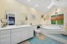 Vaulted ceiling bathroom featuring a large corner jetted tub, a window with exterior foliage, and a skylight