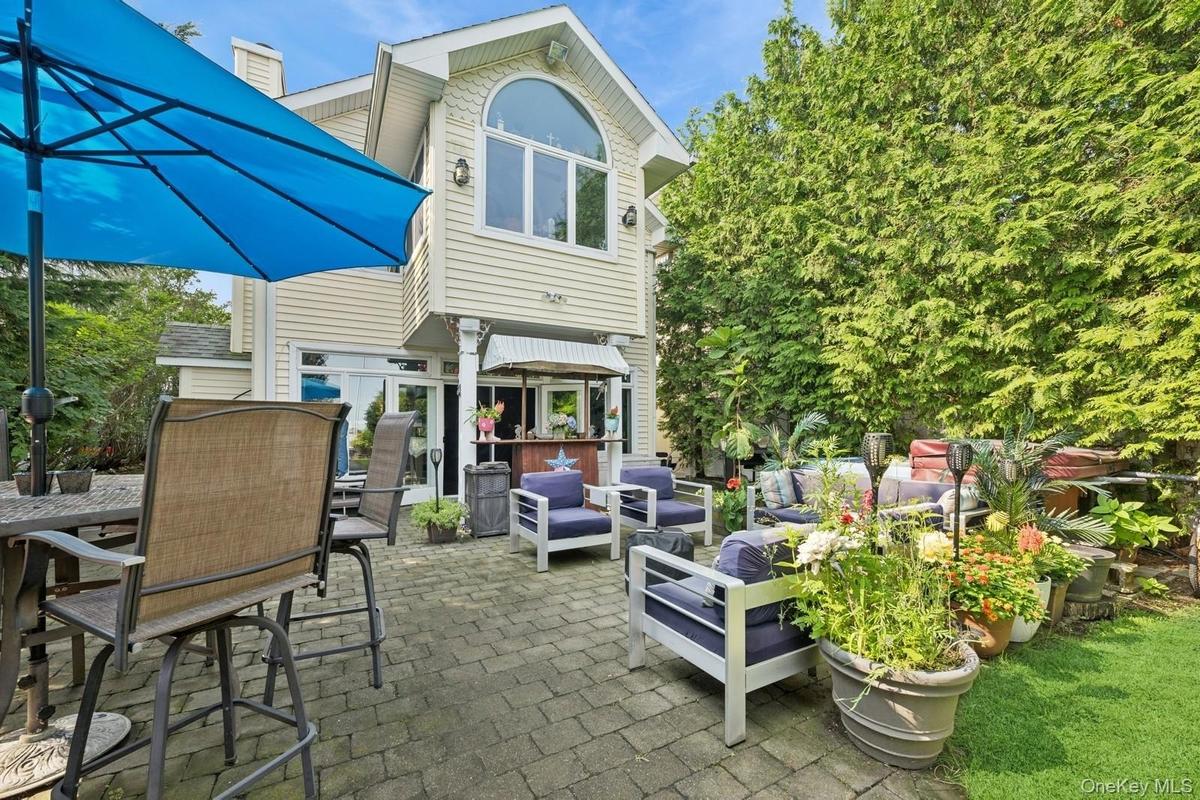 Paver patio featuring a built-in outdoor bar, a grassy area, and tall privacy trees
