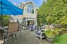 Paver patio featuring a built-in outdoor bar, a grassy area, and tall privacy trees