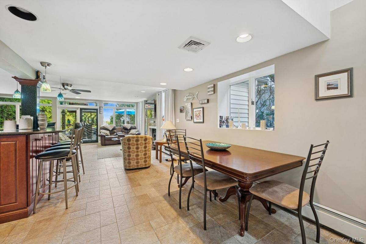 Recreational room featuring a built-in bar with pendant lighting, a ceiling fan, and large windows with outdoor access