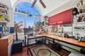 Bright sunroom featuring a large arched window, a ceiling fan, built-in shelving, wood-finish flooring, and ample desk space