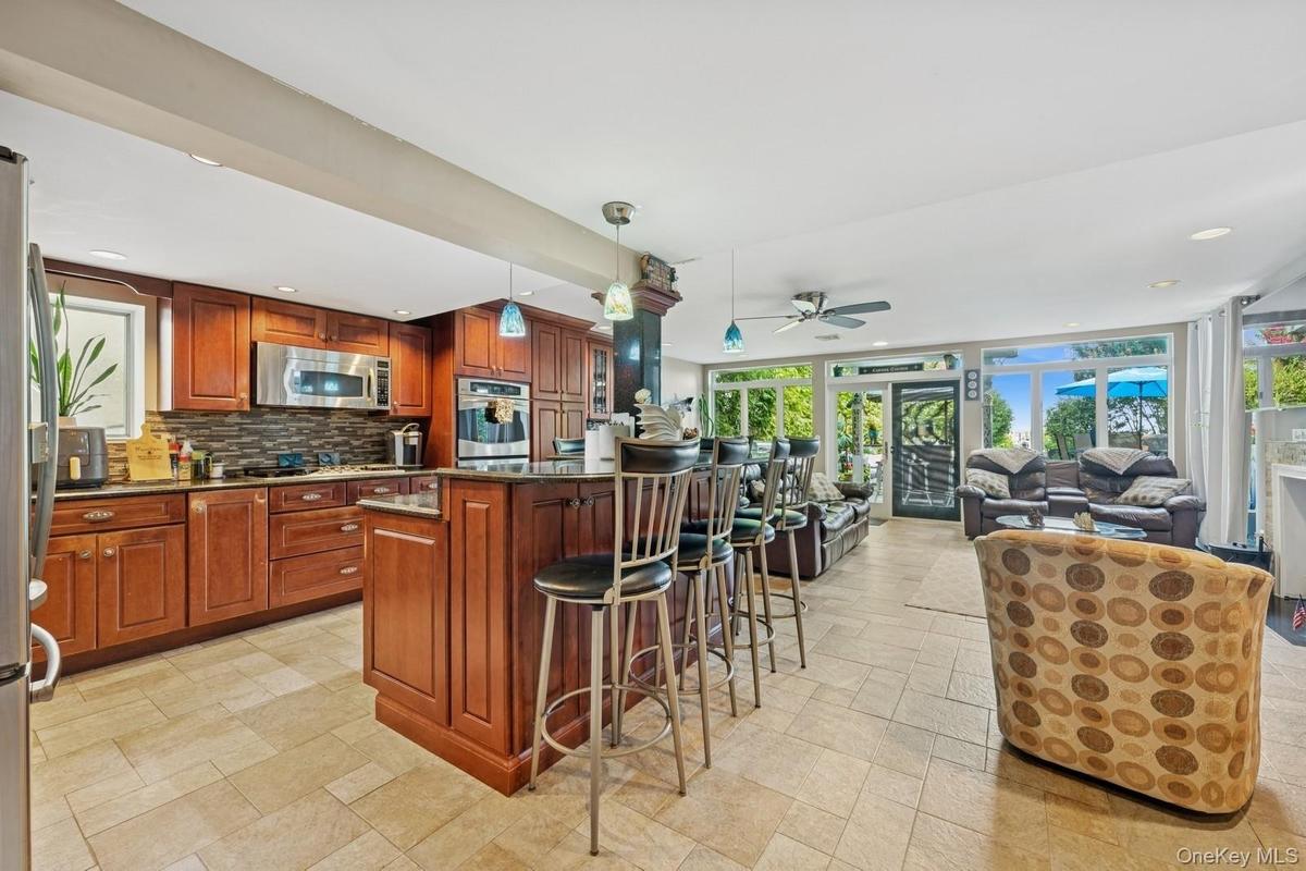 Kitchen with wood cabinetry, stainless steel appliances, and a central island with bar seating