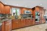 Kitchen featuring wood cabinetry, stainless steel appliances, granite countertops, and a mosaic tile backsplash