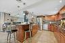 Kitchen featuring wood cabinetry, stainless steel appliances, a stone countertop, tile backsplash, and tile flooring