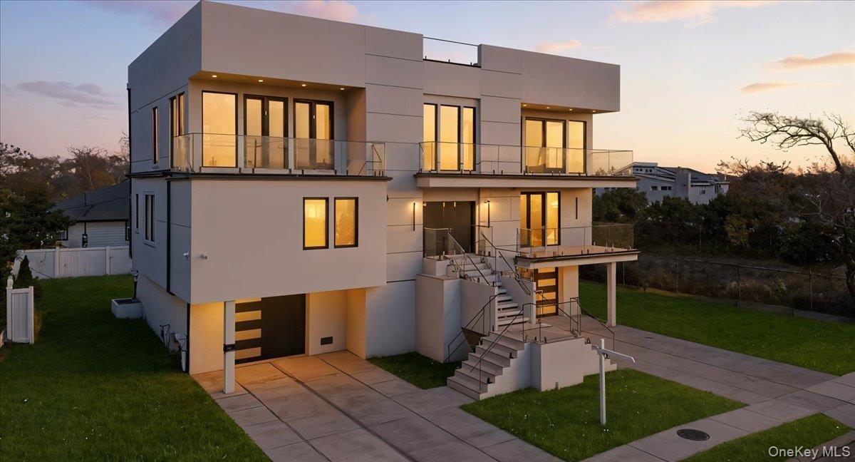 Contemporary house with stairs, a balcony, stucco siding, and concrete driveway
