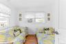 Bright room with a white door, two windows featuring white blinds, and wood-finish flooring