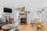 Living area featuring wood-finish flooring, a fireplace with a stone hearth, white shiplap walls, a white staircase with a paneled base, and a paneled