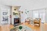 Living area featuring wood-finish flooring, a wood-burning fireplace with a slate hearth, and a white beadboard wall finish