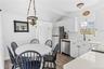 Bright kitchen and dining area featuring white cabinetry, light countertops, stainless steel appliances, and wood-finish flooring