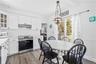 Kitchen and dining area featuring white cabinetry, a white subway tile backsplash, stainless steel range, and wood-finish flooring