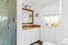 Bathroom featuring a glass-enclosed shower, single vanity with a granite countertop, and white beadboard paneling