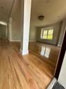 Spacious interior featuring wood-finish flooring, a contemporary ceiling light fixture, neutral wall colors, and ample natural light from a prominent 