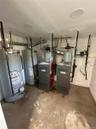 Utility room featuring two water heaters, two boilers, copper piping, and ceiling-mounted light fixtures