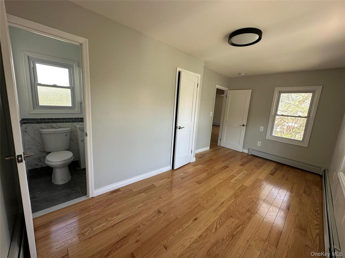 Spacious room featuring wood-finish flooring and light-toned walls