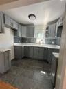 Kitchen featuring gray cabinetry, white countertops, a mosaic tile backsplash, stainless steel sink, and dark tile flooring