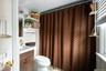 Bathroom featuring a dark wood-finish vanity, white countertop with integrated sink, white toilet, and a brown chevron-patterned shower curtain