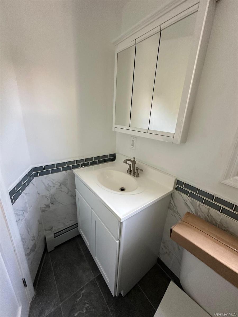 Bathroom vanity featuring a white cabinet, integrated sink, and brushed nickel faucet