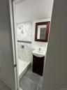 Compact bathroom featuring a shower with white marble-patterned tile surround and a decorative blue glass tile accent band