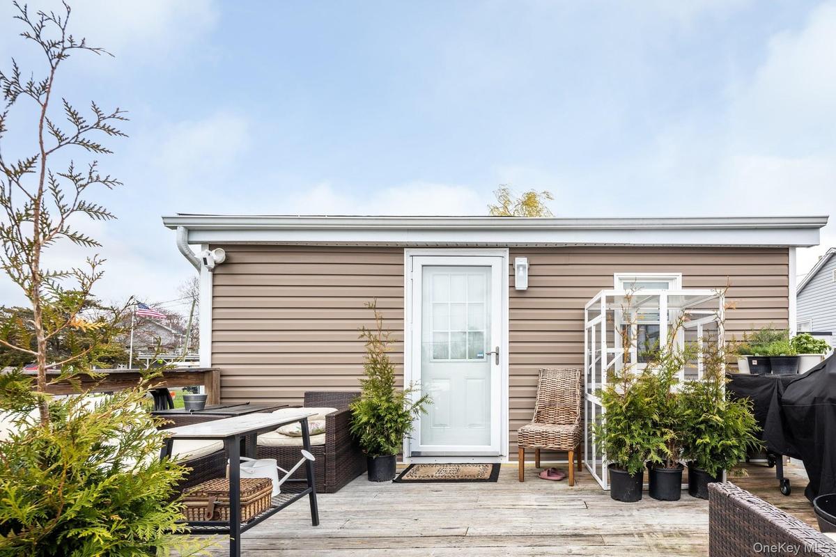 Expansive outdoor deck space featuring light-colored siding, a white storm door, and white gutters