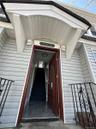 Entryway featuring a decorative overhang, light gray siding, and a rich wood-finish door with glass inserts