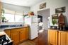 Well-lit kitchen featuring wood-finish flooring, light wood cabinetry, dark speckled countertops, and a double-basin stainless steel sink with a chrom