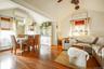 Open-concept living space featuring wood-finish flooring, vaulted ceilings, and multiple windows with natural fiber blinds