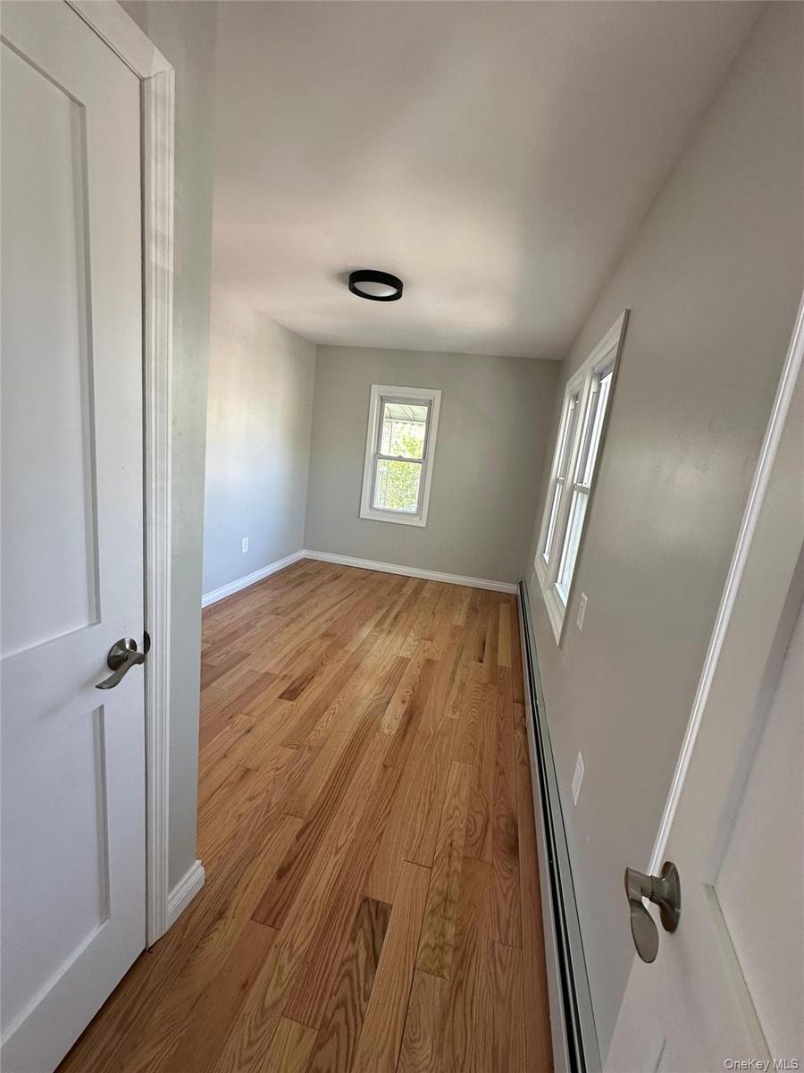 Room with wood-finish flooring, light gray wall paint, and white baseboards