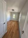 Room with wood-finish flooring, light gray wall paint, and white baseboards