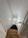 Wood-finish flooring at the landing, leading to a staircase with black carpeted treads and a white handrail
