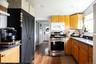 Kitchen featuring wood-finish flooring, dark stone countertops, wood cabinetry, a stainless steel range, and a built-in microwave