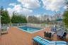 Expansive outdoor deck featuring an in-ground swimming pool, white picket fencing, and mature perimeter trees