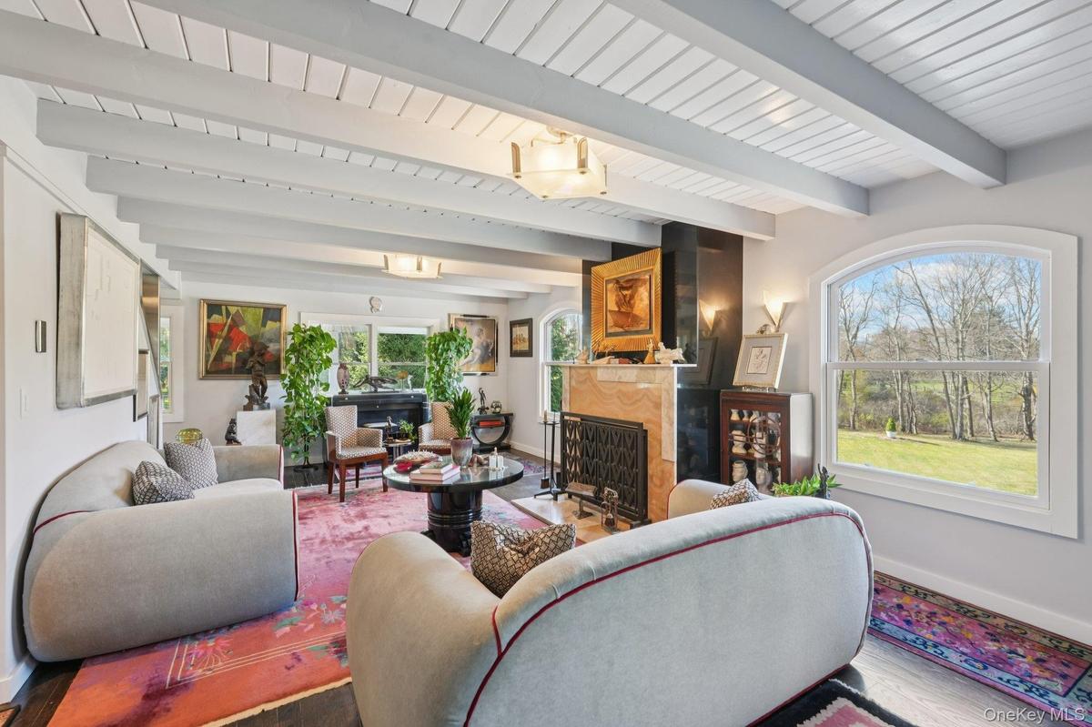 Open-concept living area showcasing exposed beam ceilings, recessed lighting, and large picture windows framing scenic landscape views