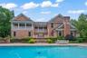 Expansive outdoor living area featuring a swimming pool, stone patio, and mature landscaping