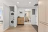 Laundry room with stacked washing machine and dryer, electric panel, light wood-type flooring, and recessed lighting