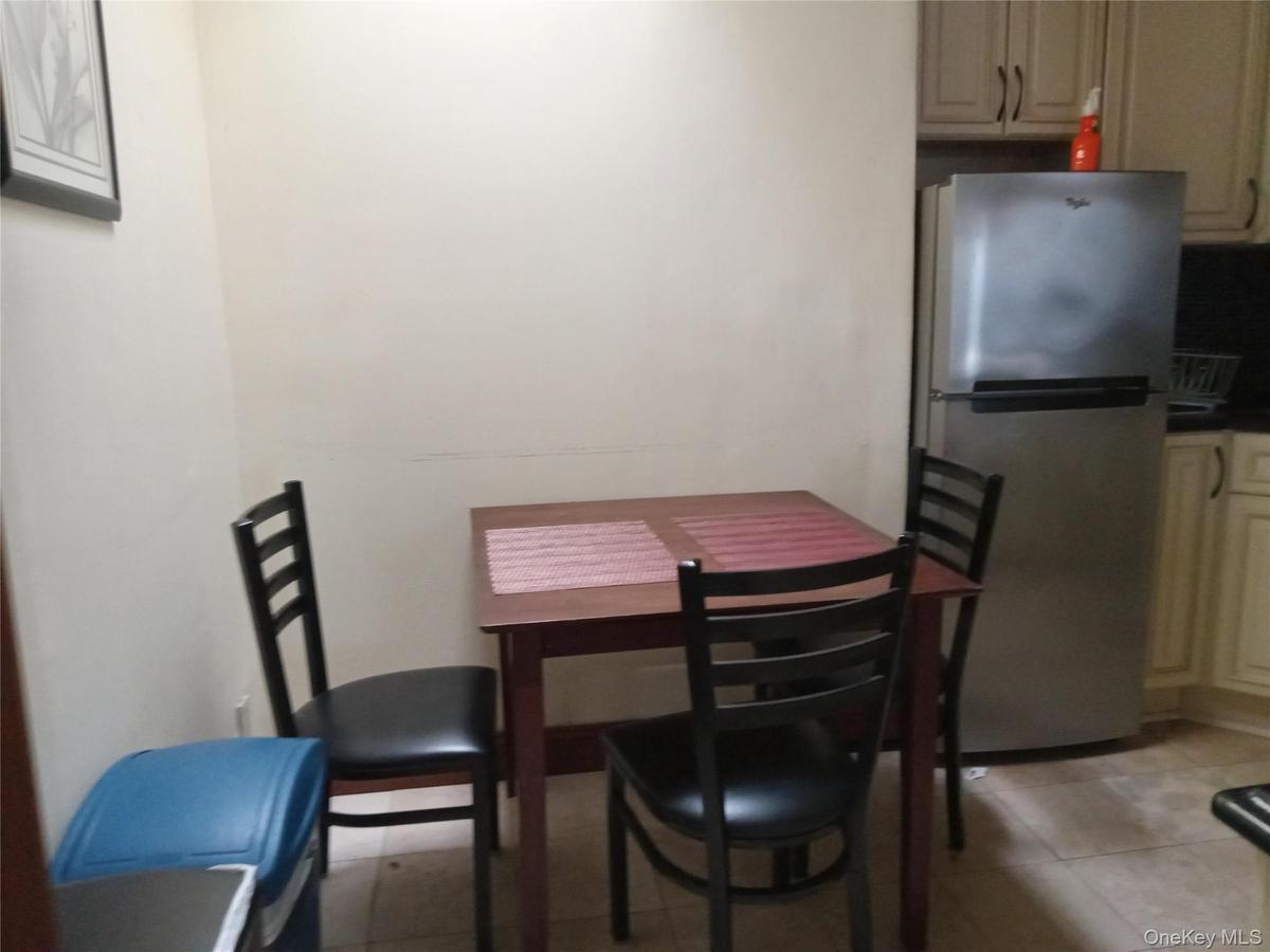 Compact dining area featuring a stainless steel refrigerator, light-toned cabinetry, and tiled flooring
