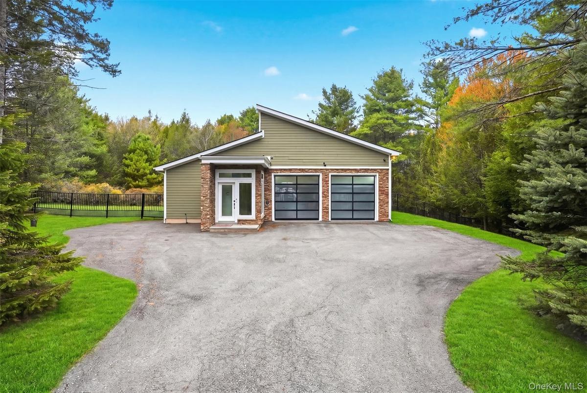 Modern ranch-style home featuring a four-car garage with frosted glass doors, a stone facade accent, and a light green exterior