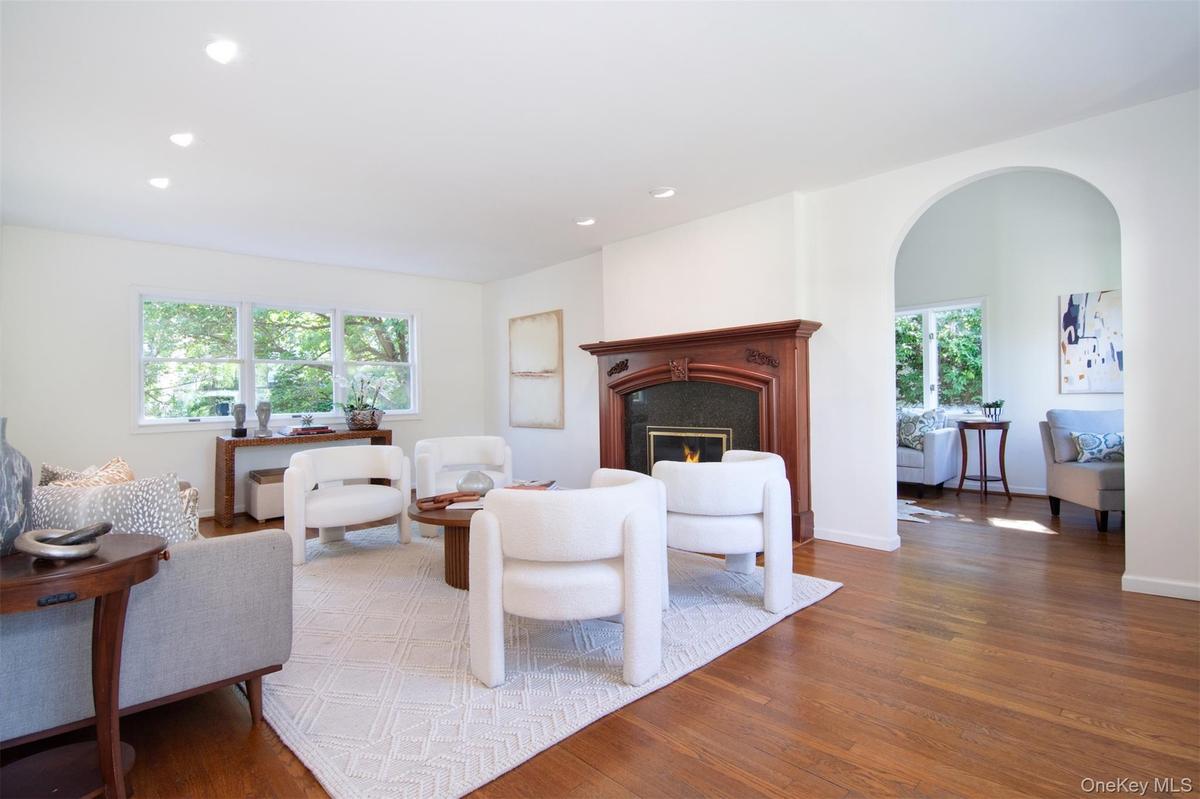 Living room with wood finished floors, recessed lighting, a fireplace, and arched walkways