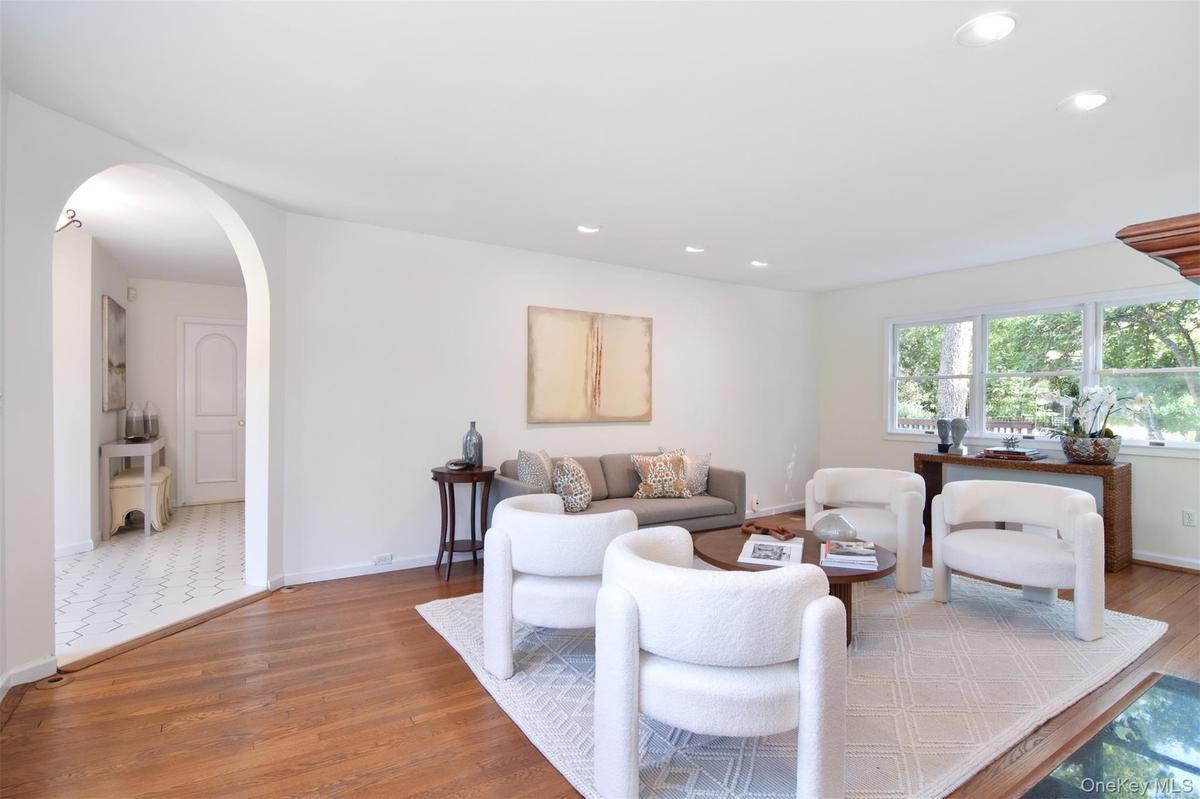 Living area featuring wood finished floors, arched walkways, and recessed lighting