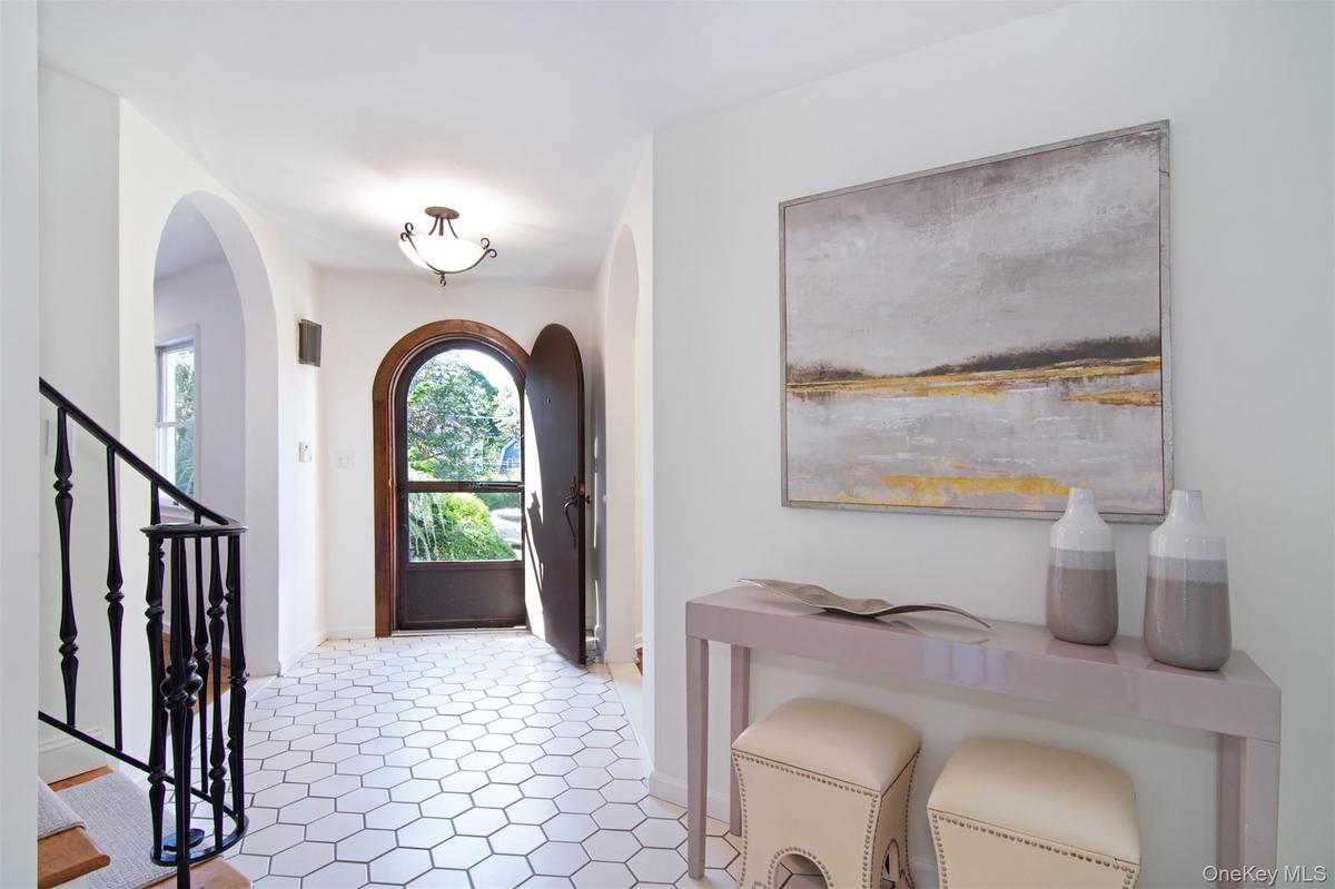Foyer entrance featuring stairs, arched walkways, and light tile patterned floors